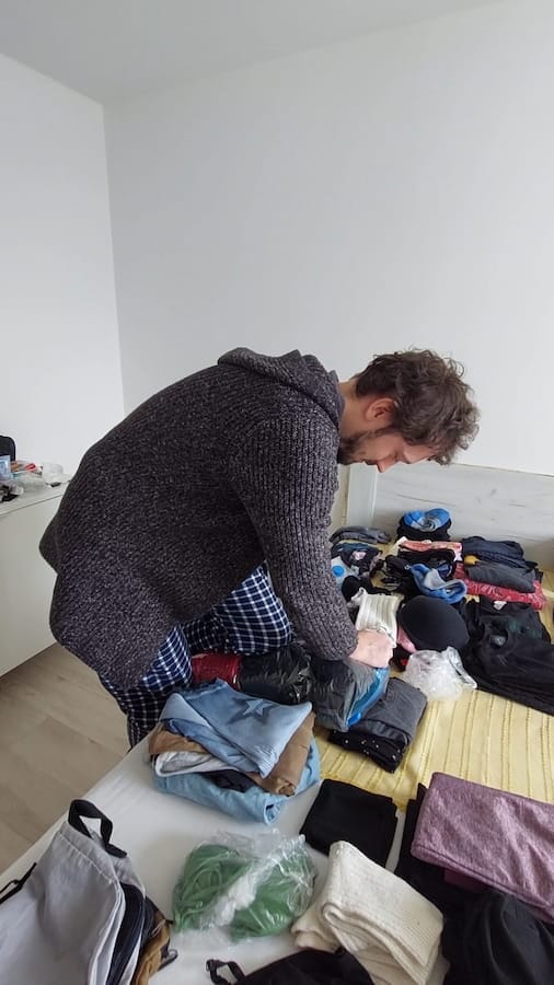 Daniel packing clothes on a bed