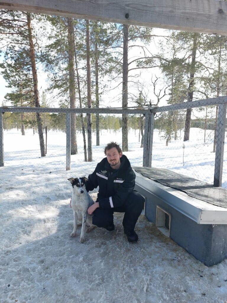 Daniel crouching next to a husky puppy