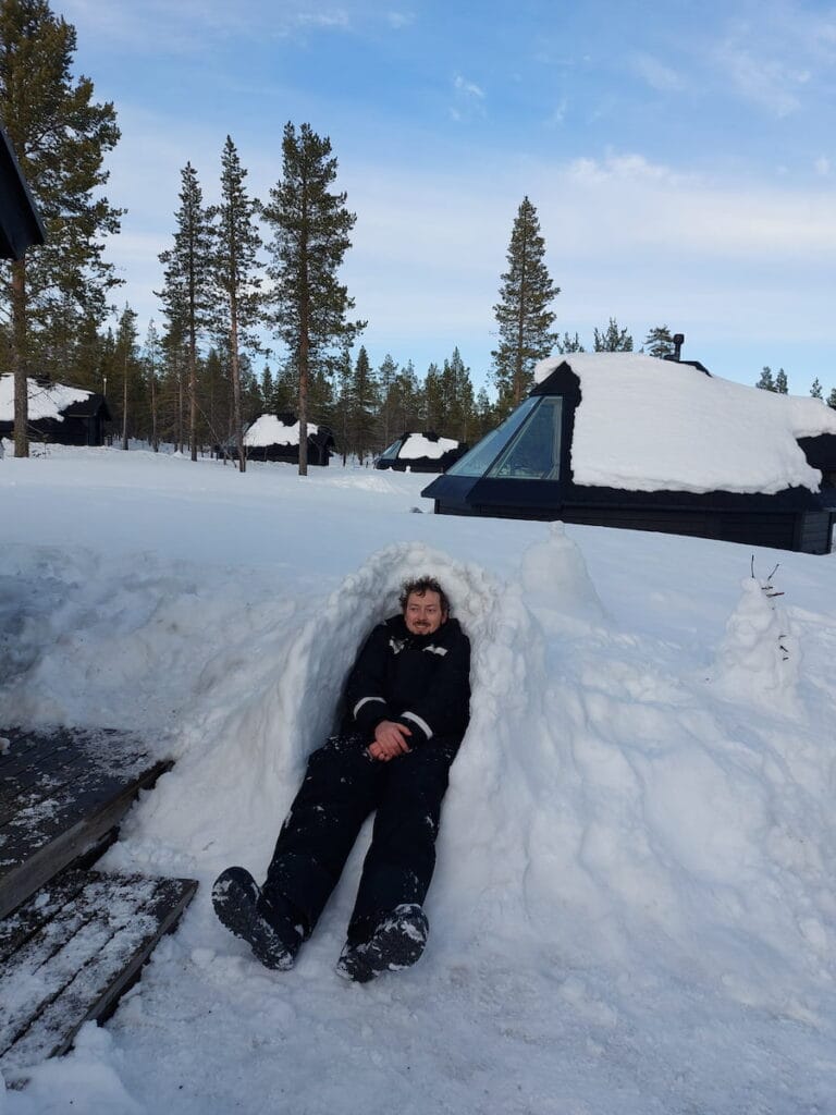 Daniel lying in a half-igloo in the snow