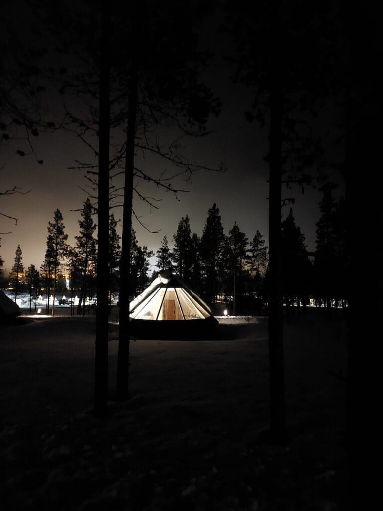 A lit up glass-roof cabin at night