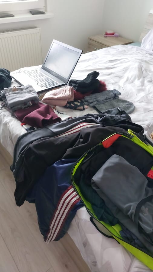 Clothes and a laptop on a bed