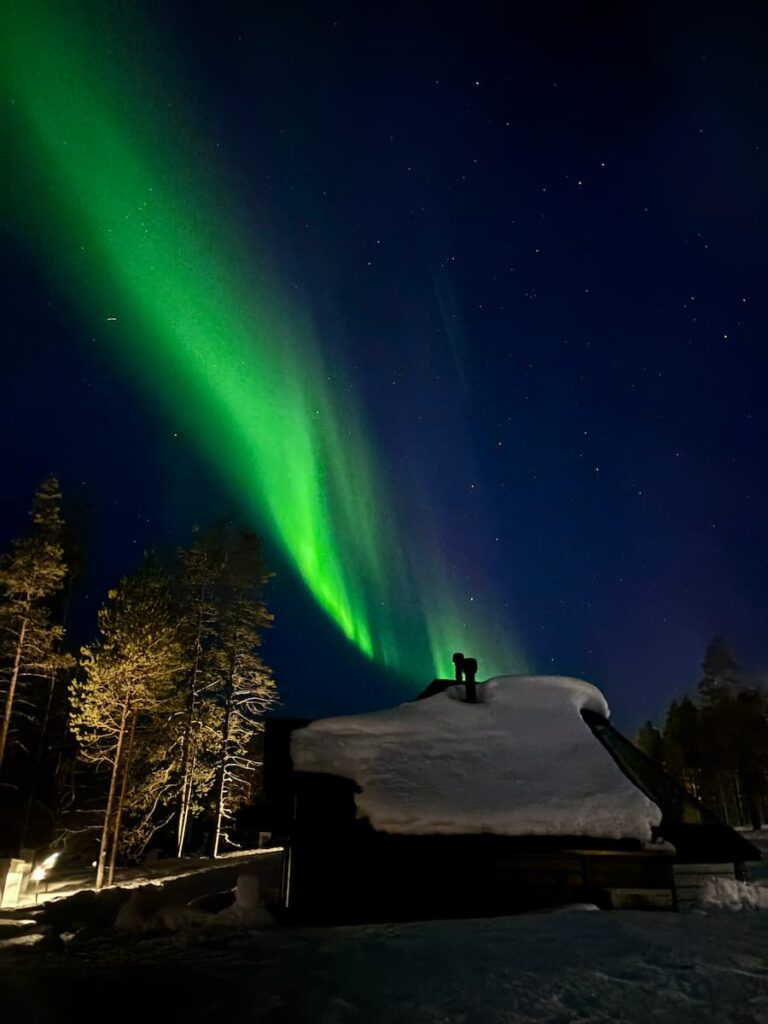 Aurora above a snowy cabin