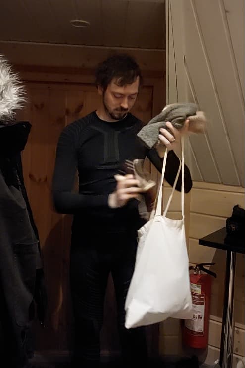 Daniel packing winter hats into a tote bag
