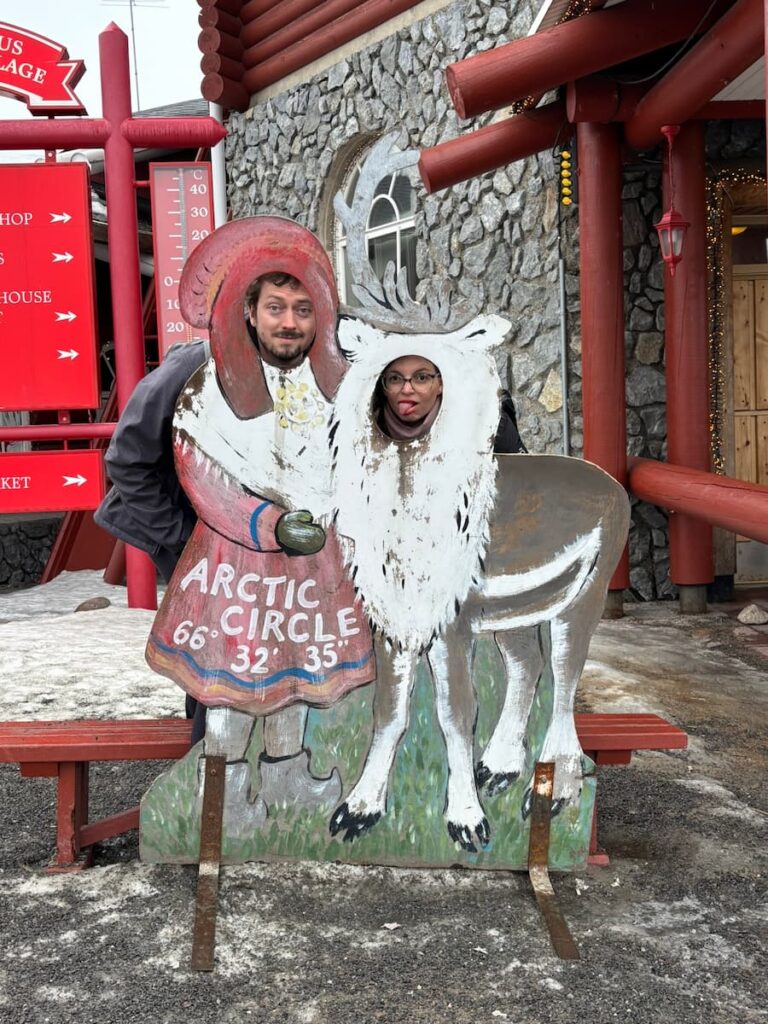 Mirka and Daniel posing behind a reindeer and Santa cutout