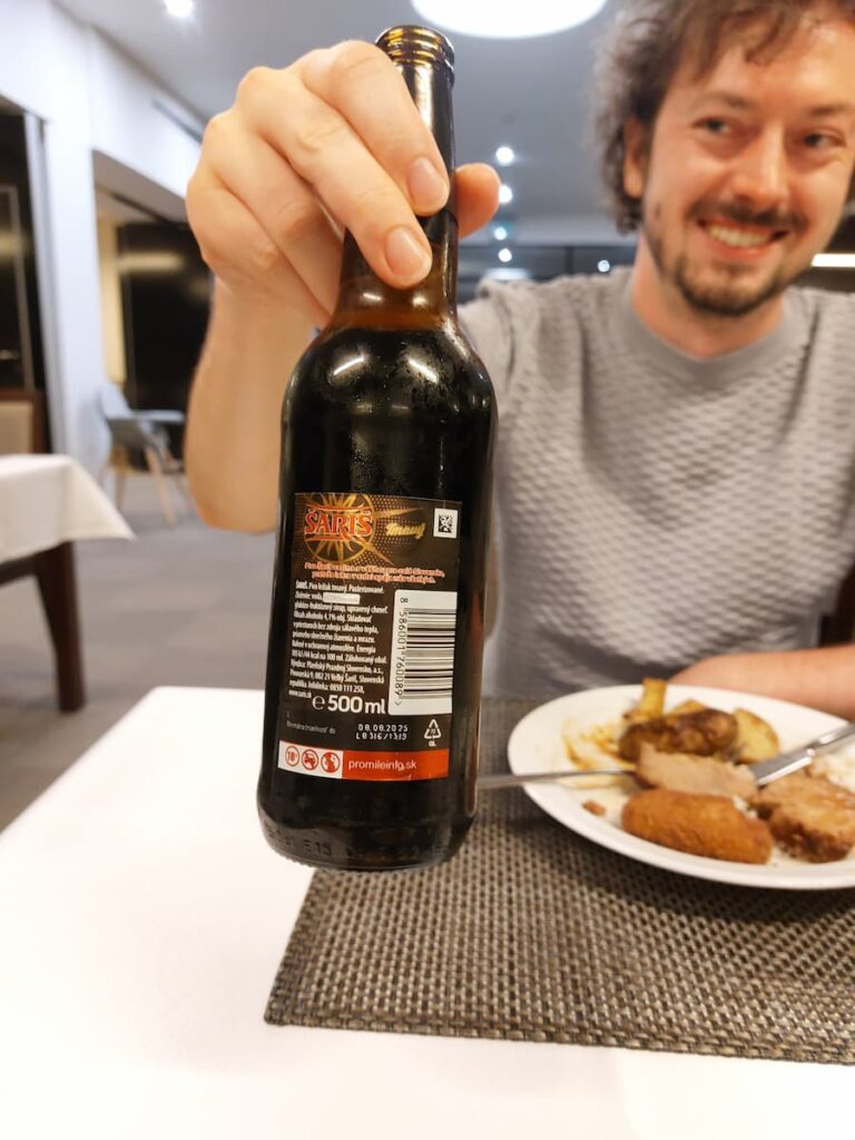 Enchanted…ish: Our Shockingly Bad 4 Star Hotel Stay in Slovakia 10 Daniel holding a bottle of dark beer