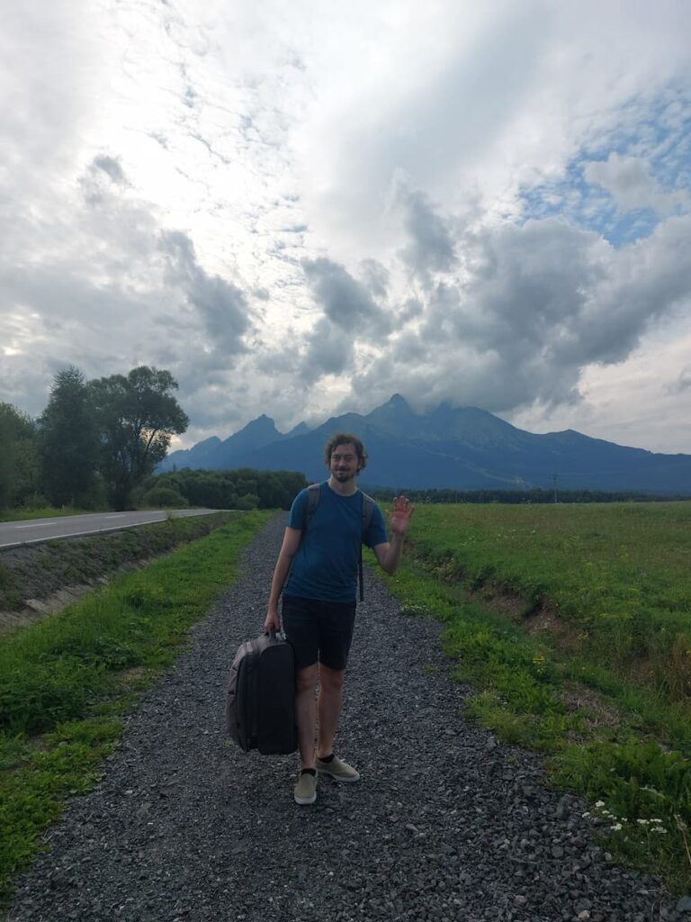 Daniel carrying a suitcase on a gravel path in the High Tatras