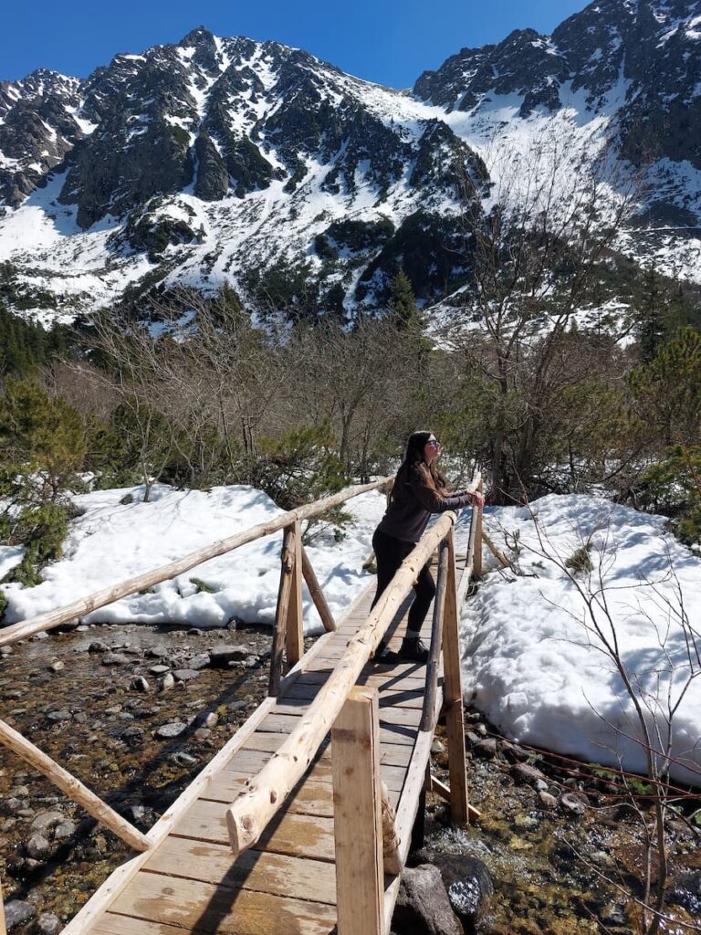 Mirka standing on a bridge beneath a snowy mountain