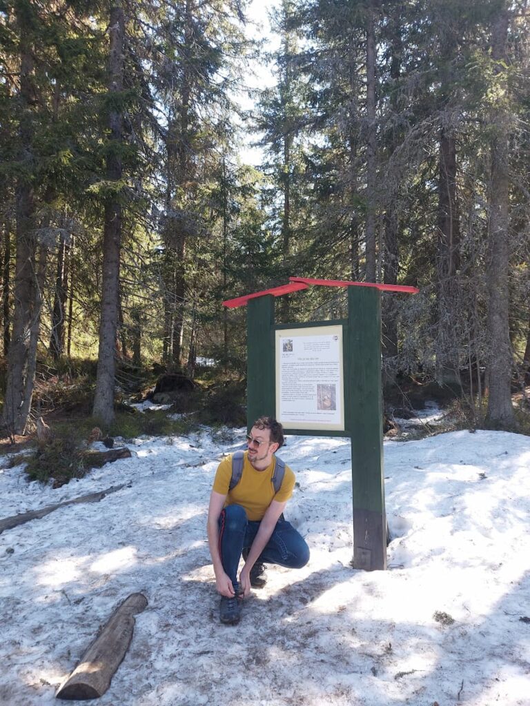 Daniel tying his shoelaces in the snow wearing a short-sleeve Tee