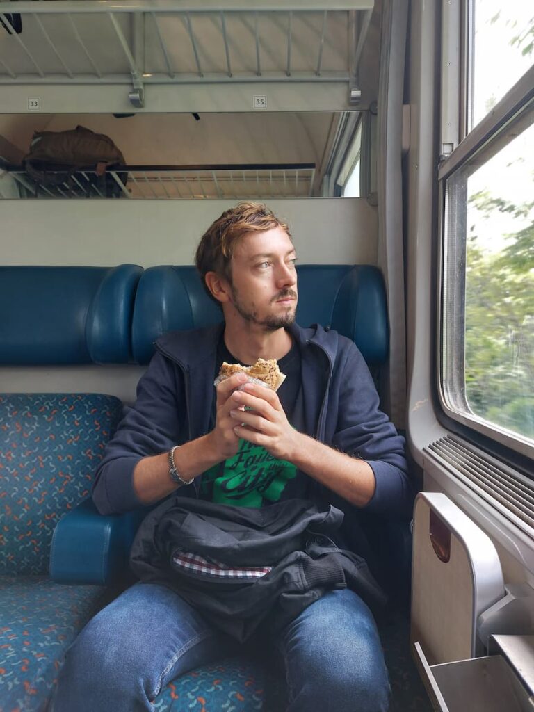 Daniel eating a roll on a train