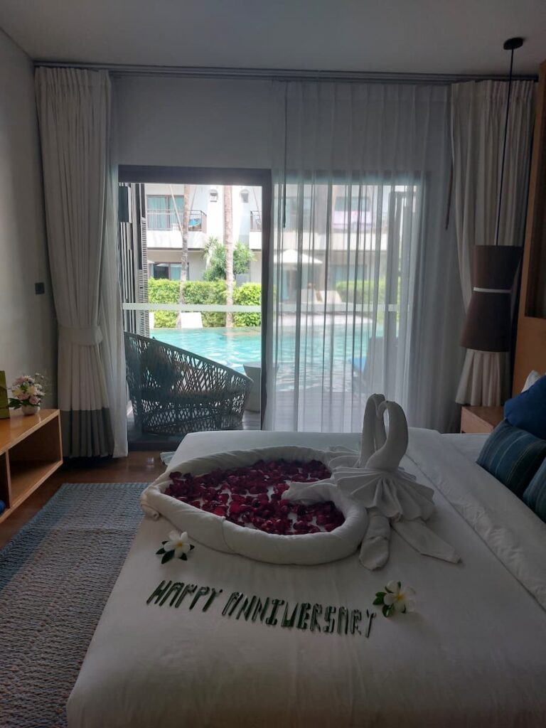 Bedroom with happy anniversary wish on a bed with a pool in the background
