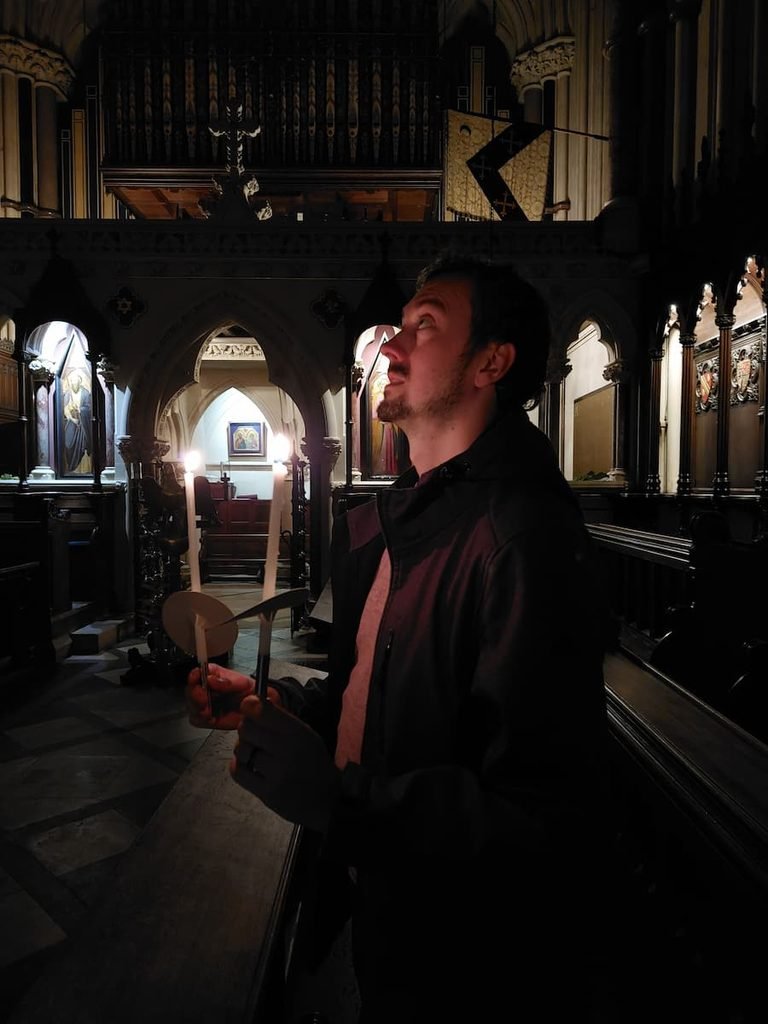 Daniel holding candles during a candlelit evensong at Exeter College